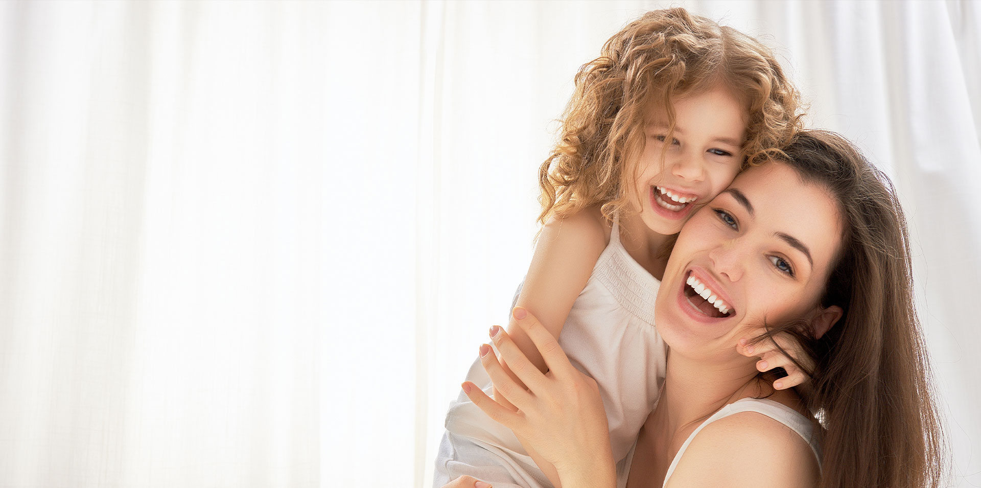 A woman and a young child are embracing each other with smiles on their faces.