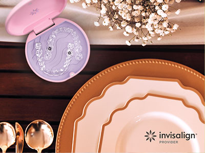 The image shows a table setting with various plates, bowls, and utensils, including a toothbrush holder with brushes and a box of dental floss, on a wooden surface, accompanied by a marketing banner for Invisalign.