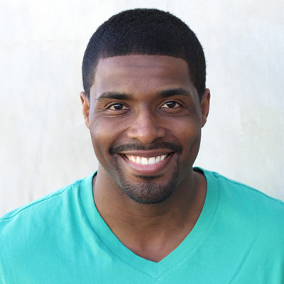 The image shows an elderly couple smiling and embracing each other outdoors during daylight.