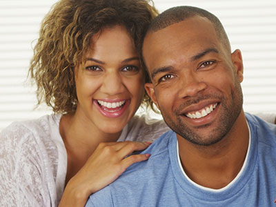 A man and woman posing together with smiles, sharing a warm moment captured in a portrait-style photograph.