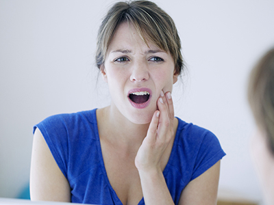 A woman with surprised facial expression, looking at her own hand on her mouth.