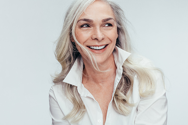 A woman with short blonde hair, wearing a white shirt, smiling at the camera.