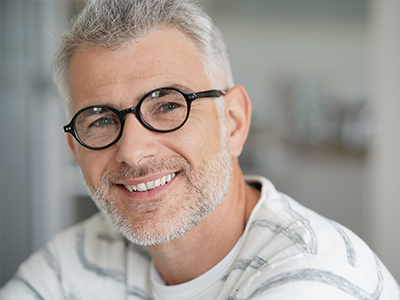 The image shows a man with glasses smiling at the camera.