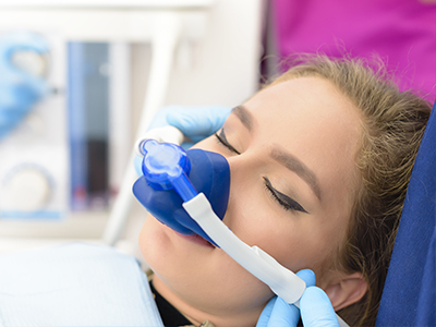 Woman receiving medical treatment with oxygen mask on her face while lying down.