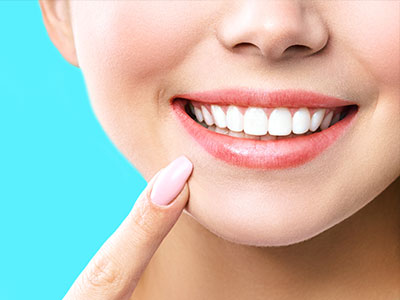 The image shows a close-up of a person s face with a bright smile, featuring white teeth and applying lipstick, against a blue background.